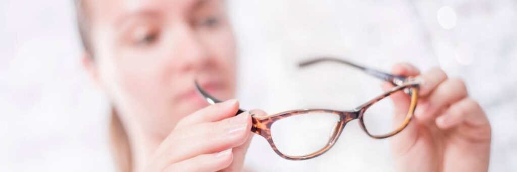 Dziewczyna ogląda swoje okulary. Obrazek w artykule Jak powinny leżeć okulary na nosie? Przewodnik dopasowania okularów