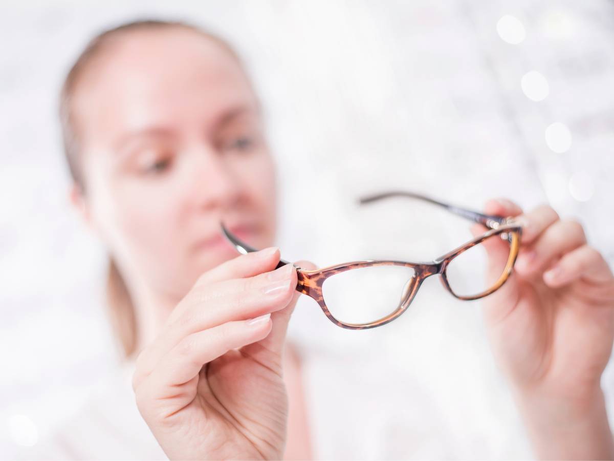 Kobieta ogląda okulary. Obrazek w artykule Porysowane okulary. Poradnik jak skutecznie usunąć zarysowania z okularów