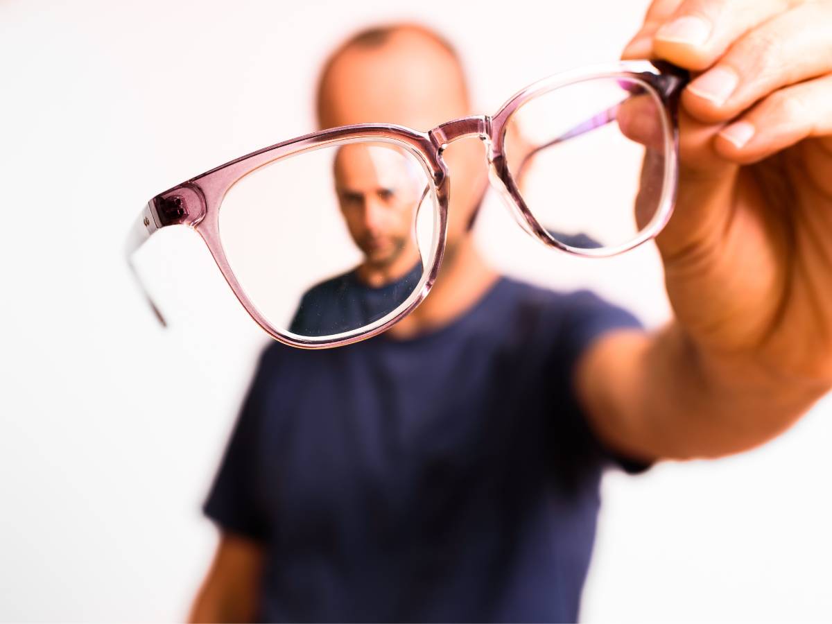 Mężczyzna z okularami w dłoni. Obrazek w artykule Za mocne okulary objawy. Jak rozpoznać, że szkła są za mocne?