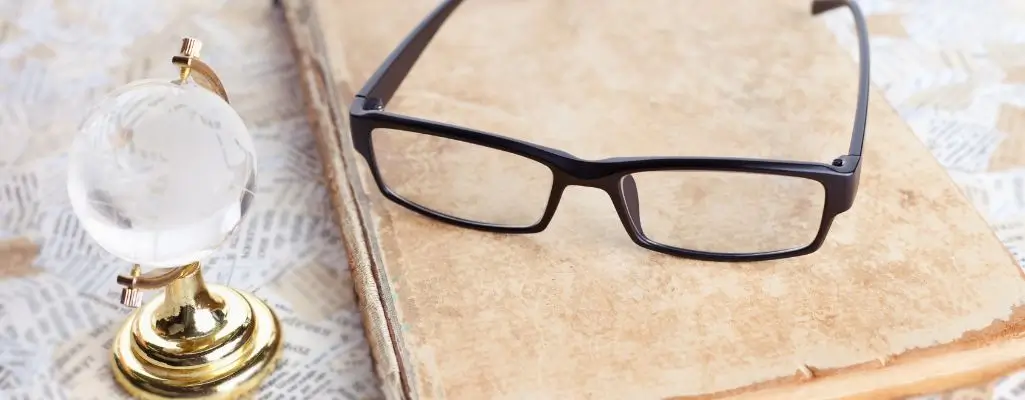 Obrazek wyróżniający do artykułu - okulary do czytania. Widoczny okulary leżące na książce obok szklany globus.